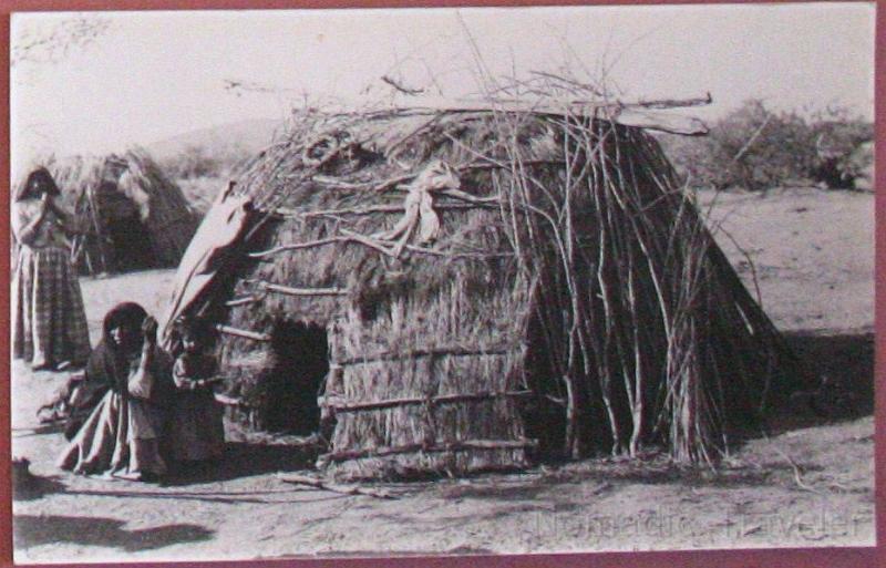 IMG_9897-hut.JPG - O'odham women and children pose outside their brush houses on the San Xavier Reservation. Martinez Hill,  now east of I-19 is visible in the background. Taken 1894.